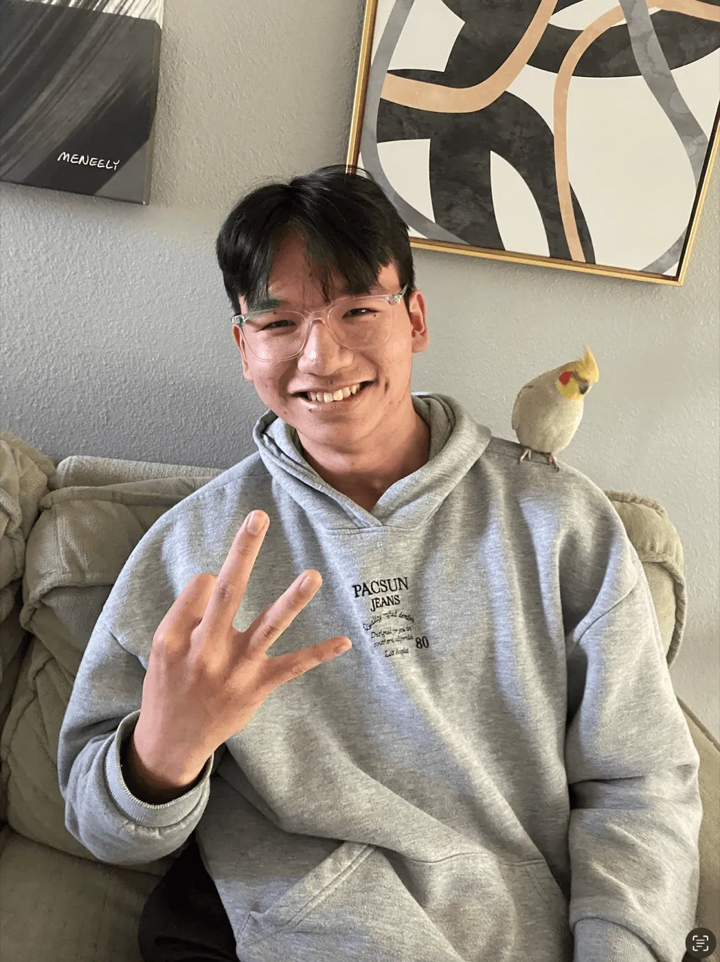 Francis smiling on a couch with a cockatiel on his shoulder