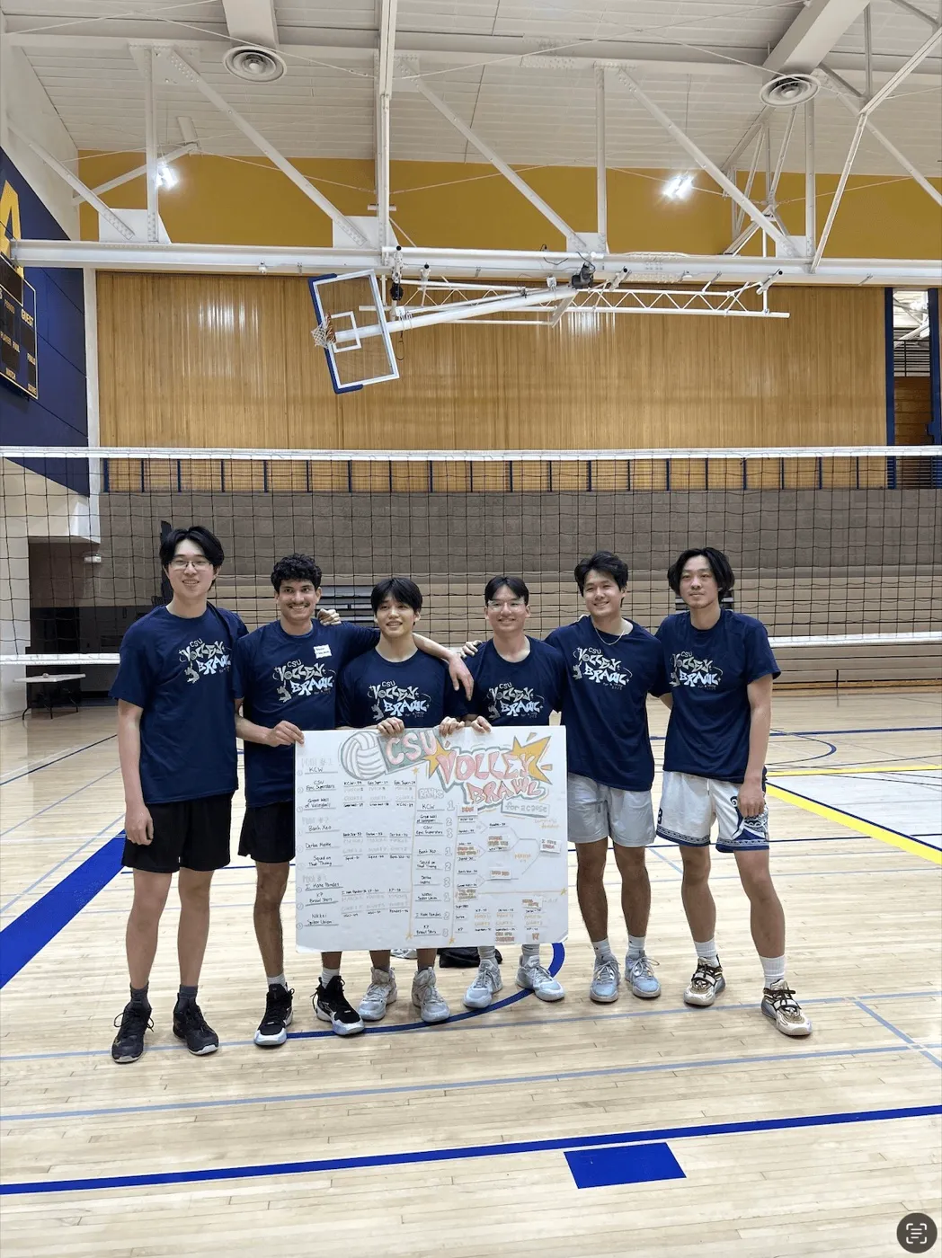 Francis and his volleyball team holding a winners sign in a gym